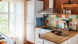 A kitchen with a white refrigerator, a stove, a coffee maker, and a colorful tiled backsplash. - Nachhaltig und gefühlvoll in Seenähe by Interhome (Gnesta)
