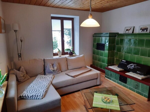 Ein Wohnzimmer mit einer Couch, einem Glastisch und einer grün gefliesten Wand.
