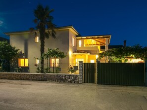 Ein zweigeschossiges Haus mit einer Steinmauer und einem Metallgitter vor der Fassade.