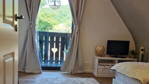 A bedroom with a large window, a bed, a TV, and a view of greenery outside. - Schwarzwald Königin by Interhome (Bühlertal)