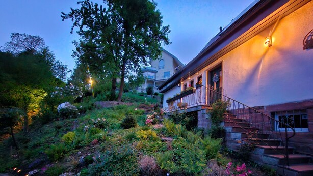 A garden with a variety of plants and flowers, a stone wall, and a building with a staircase. - Schwarzwald Königin by Interhome (Bühlertal)