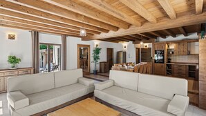 Amplia sala de estar con dos sofás, una mesa de centro de madera y una cocina con alacenas y electrodomésticos de madera.
