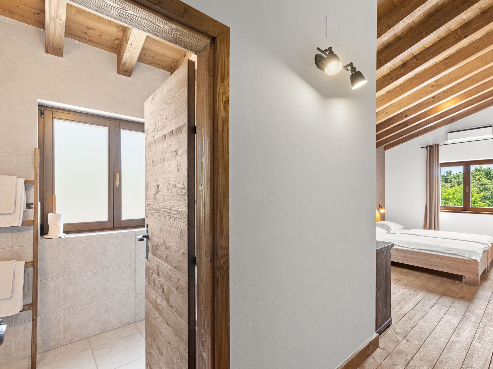 Une chambre moderne avec un plafond en bois, une grande fenêtre et un lit.