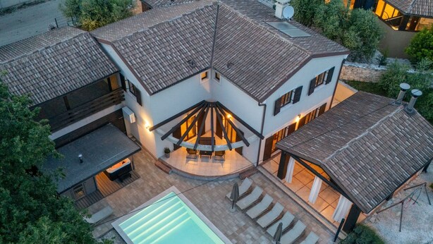 Una casa moderna con piscina, mobiliario de exterior y terraza cubierta.