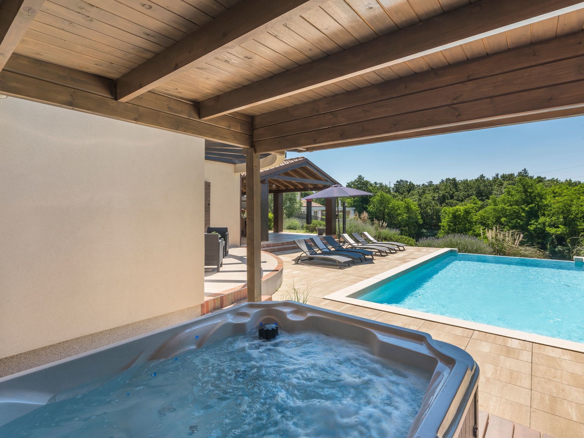 A pool area with a hot tub, lounge chairs, and a pergola.