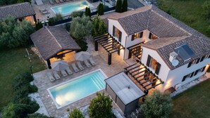 Uma casa grande e moderna com piscina, área de estar externa e um jardim bem cuidado.