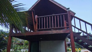 Una pequeña construcción de madera con balcón, una puerta verde y una escalera que conduce a ella.