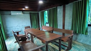 Una habitación con una mesa de madera y bancos, cortinas verdes y un suelo con diseño de mármol.