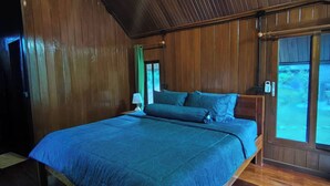 Un dormitorio con techo de madera, una cama grande con ropa de cama azul y una ventana con vistas al exterior.