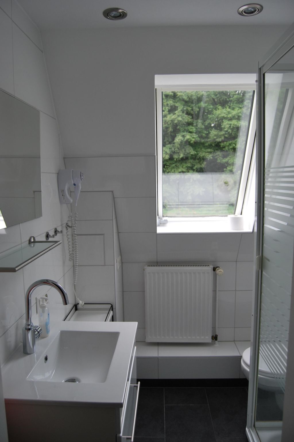 Een moderne badkamer met een groot raam, een inbouwspoelbak en een douchecabine.