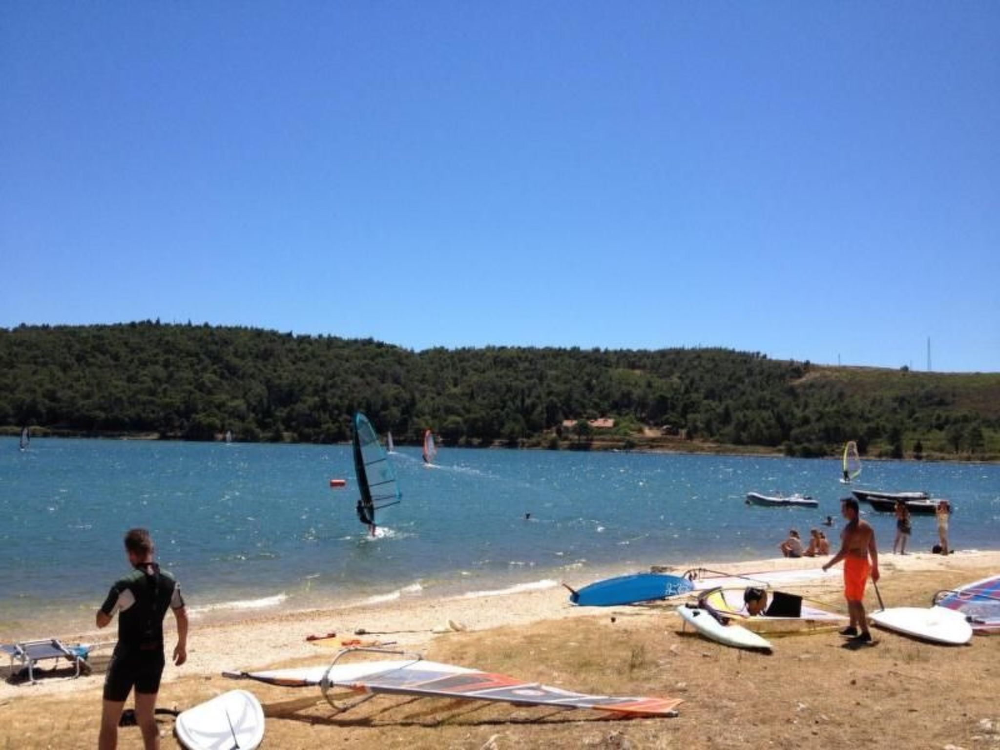 Ein Strand mit Windsurfgeräten und einigen Personen.