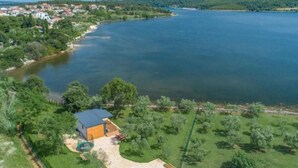 Ein Anwesen am Seeufer mit Haus, Schwimmbad und gepflegtem Rasen.