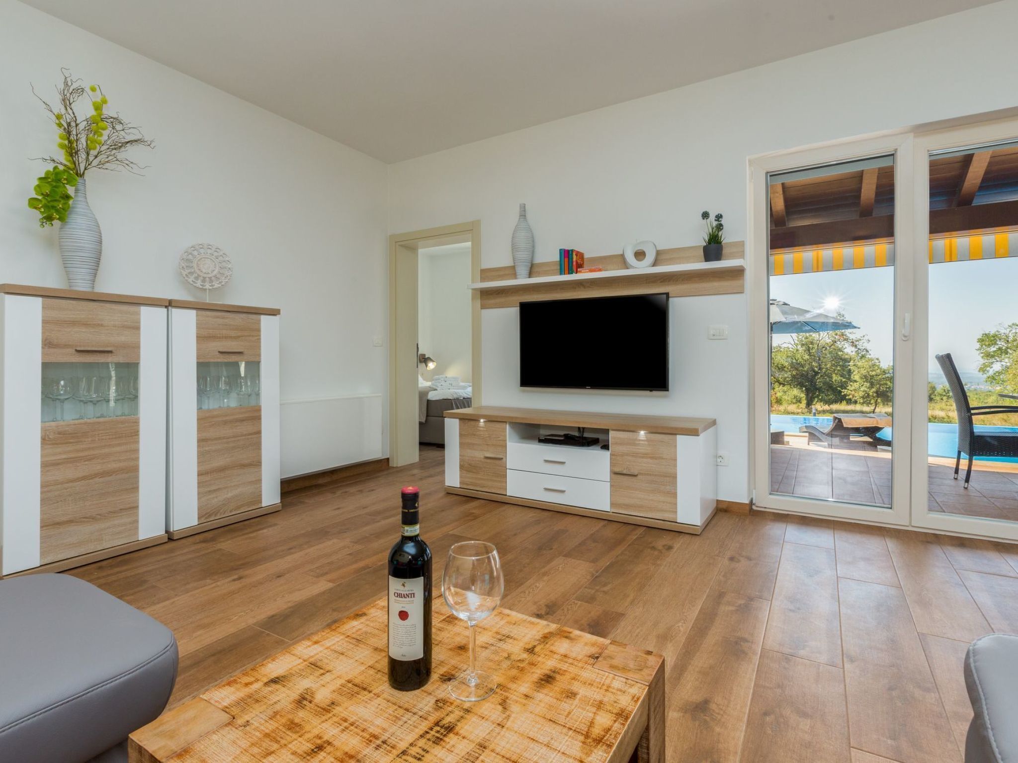 Ein modernes Wohnzimmer mit Fernseher, Holzkästen und einer Essecke mit Tisch und Stühlen.