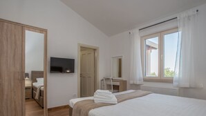 Ein Schlafzimmer mit einem Bett, einem Schreibtisch, einem Sessel, einem Fernseher und einem Kleiderschrank.