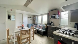 Un espacio habitable compacto con kitchenette, comedor y sofá con cojines estampados.