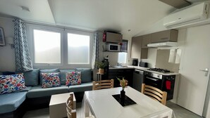 Un espacio habitable compacto con kitchenette, zona de comedor y sofá con cojines estampados.