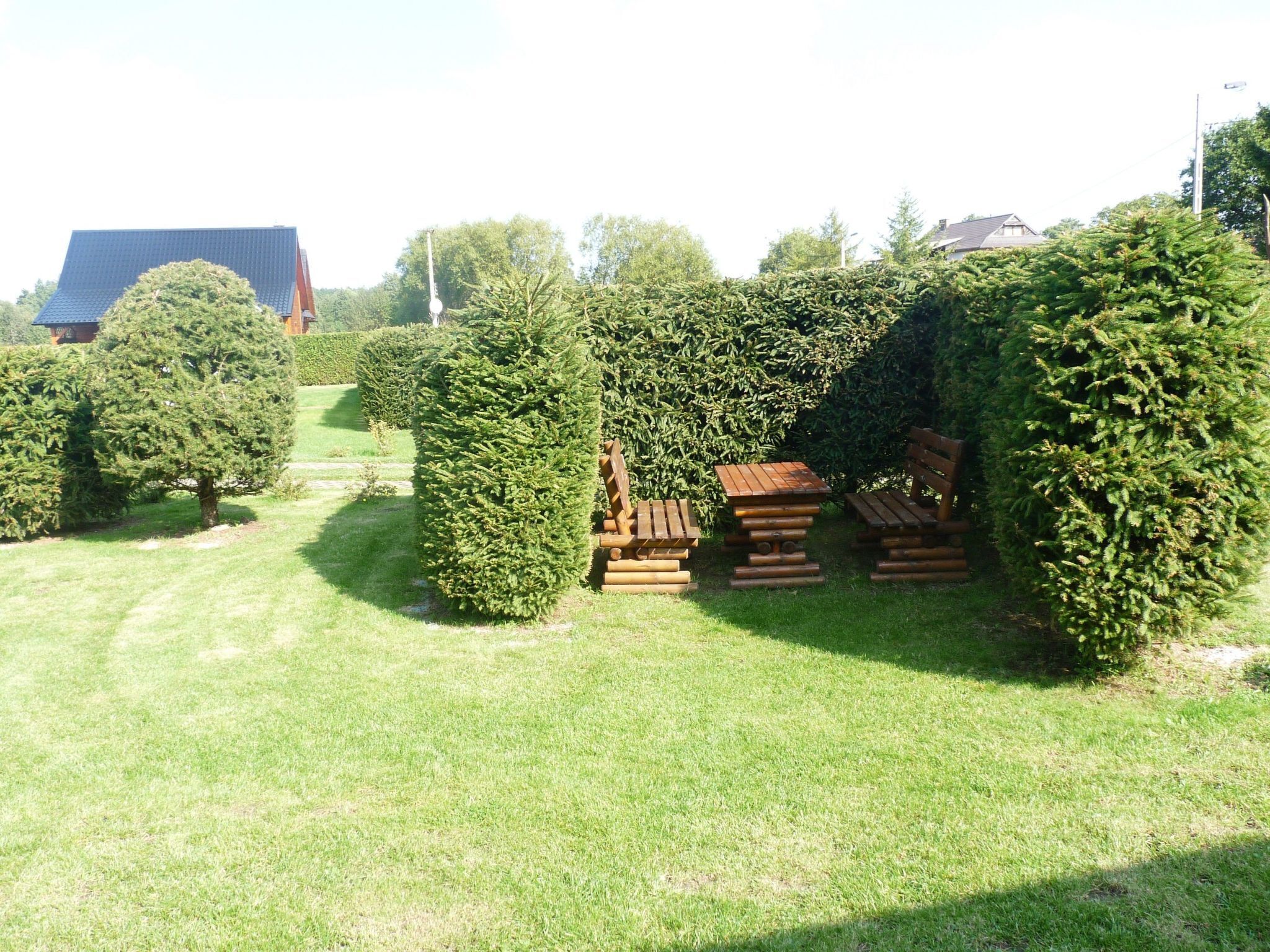 A well-maintained garden with neatly trimmed hedges, a wooden bench, and a picnic table.