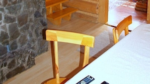 A wooden interior with a stone wall, a wooden staircase, and a table with chairs. - Holzhäuschen Goral by Interhome (Kopalino)