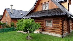 A log cabin with a steeply pitched roof, a chimney, and a small tree in the front yard. - Holzhäuschen Goral by Interhome (Kopalino)