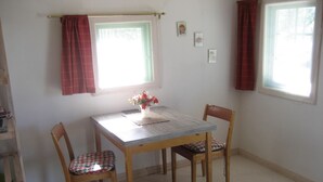 Un comedor con una mesa y sillas de madera, un florero con flores y una ventana con cortinas.
