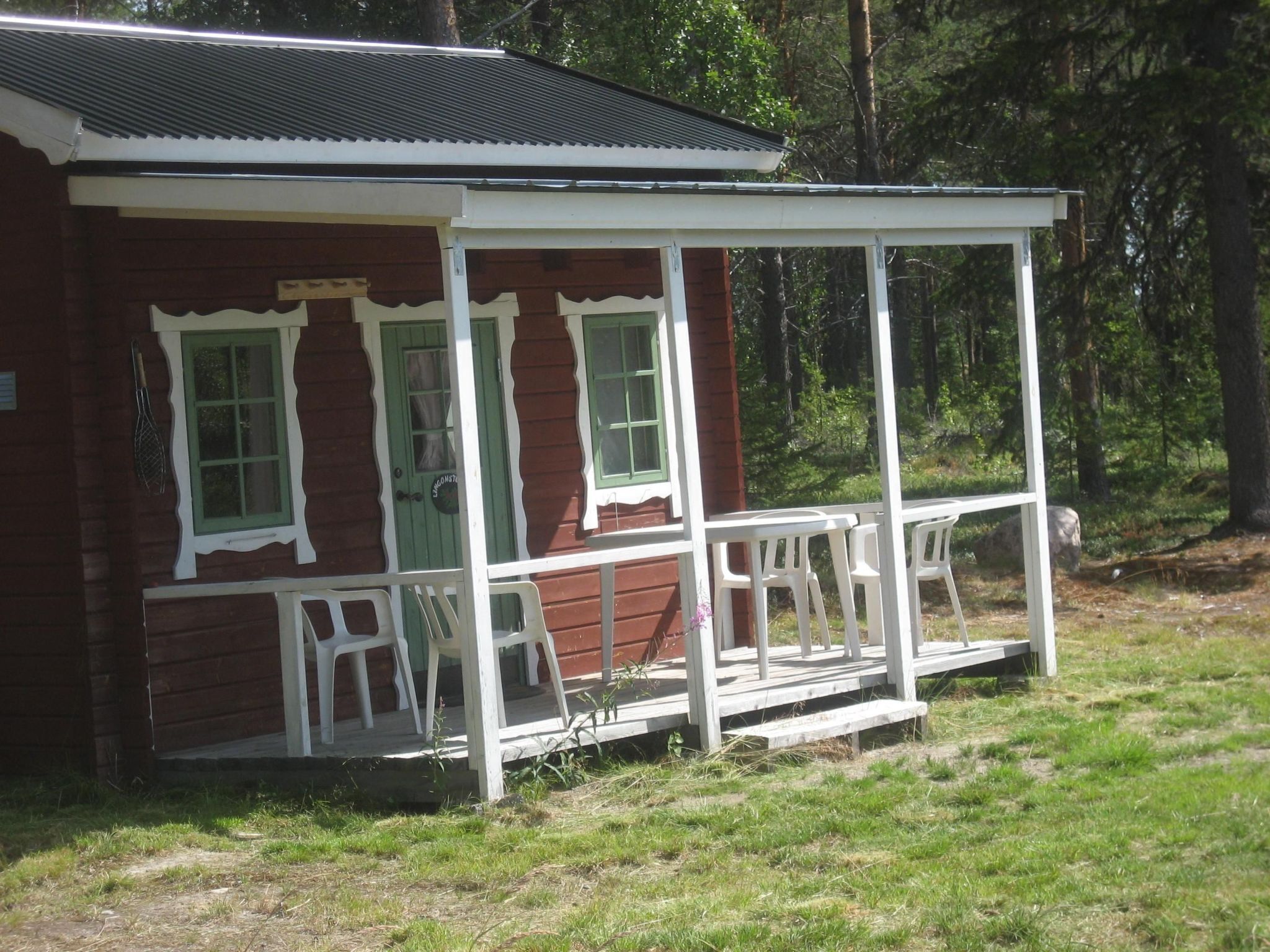 A small, rustic cabin with a porch and two windows.