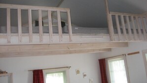 Una habitación con literas, dos ventanas con cortinas y un estante con objetos.