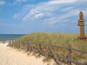 A beach with a wooden fence and a signpost indicating distances to nearby locations. - Holzhaus Juhas by Interhome (Kopalino)