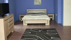 Quarto com cama, televisão sobre um penteado e pintura na parede.