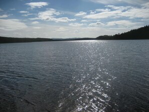 Un lac paisible, avec un ciel dégagé et des montagnes à l'horizon.
