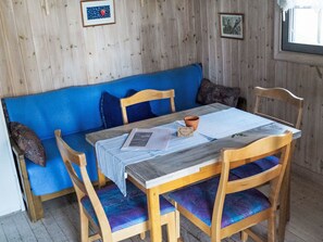Ein Holzinnenraum mit einem blauen Sofa, Holzstühlen und einem Tisch mit Unterlage.