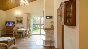 Un soggiorno accogliente con soffitto in legno, televisione, tavolo da pranzo e camino.