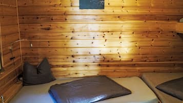 Una habitación tipo cabaña de madera con una cama, almohadas y un cuadro colgado en la pared.