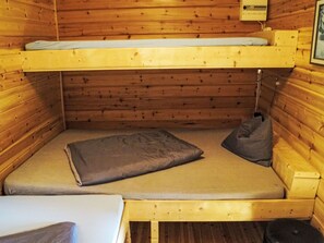 Un lit superposé avec un matelas et des oreillers, des murs en bois et une petite table.