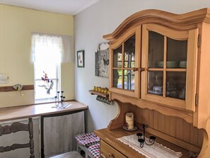 Cozinha com armário de madeira, janela com cortinas e um pequeno banco.