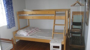 A bunk bed with a small white stool and a wooden chair.