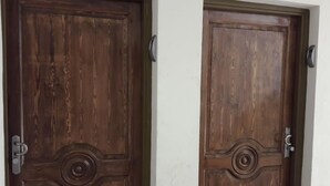 Twee houten deuren met een rond ontwerp in het midden, een handgreep en een slot aan de rechterkant.