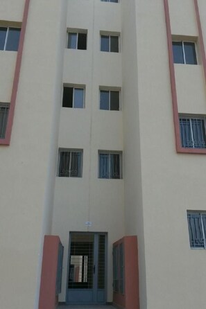 A multi-story building with a central entrance, multiple windows, and a red and beige color scheme.