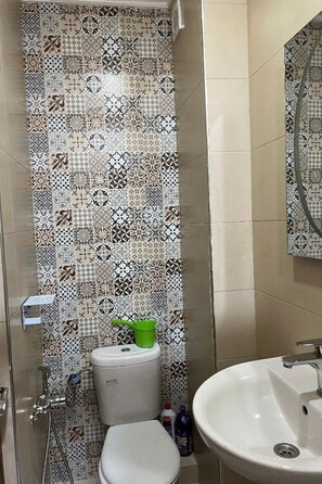 A bathroom with a patterned tile backsplash, a toilet, a green bucket, a sink, and a mirror. - Appartement Essalam by Interhome (Agadir)