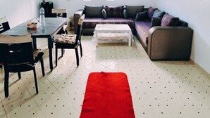 A living room with a dining area, a ceiling fan, a window with blinds, and a red rug. - Wohnung "Loft in Tanger" by Interhome (Tanger)