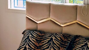 A bedroom with a bed, a window with blue metal bars, and a view of greenery outside. - Wohnung "Loft in Tanger" by Interhome (Tanger)