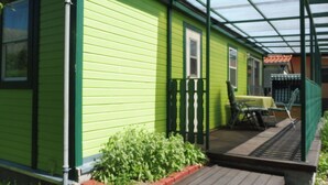 Una casa verde con veranda coperta, una finestra e un piccolo giardino.