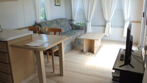 Un ambiente compatto con divano, tavolo da pranzo e televisione.