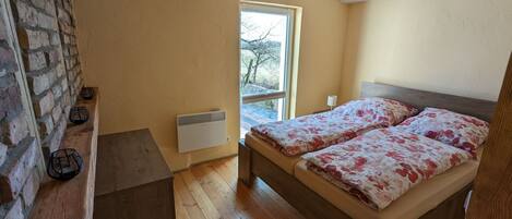 A bedroom with a wooden bed, a window, a radiator, and a brick wall.