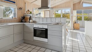 A modern kitchen with white cabinets, a Bosch oven, and a large window providing natural light. - "Yma" - 250m from the sea by Interhome (Juelsminde)