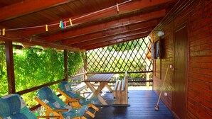 Un'area salotto all'aperto coperta, con sedie di legno e un tavolo da picnic.