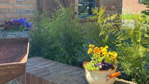 A brick building with a window and a wooden door. There are potted plants with flowers in front of the building. - Alte Schmiede by Interhome (Boitzenburger Land)