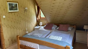 Ein gemütliches Schlafzimmer im Dachgeschoss mit einem Holzbett, einem Nachttisch mit Lampe und einem gerahmten Bild an der Wand.