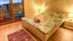 A cozy wooden room with a bed, a nightstand, and a window overlooking a deck. - "Cottage6" in einem eingezäunten Gebiet by Interhome (Mielno)