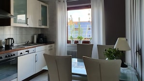 A modern kitchen with white cabinets, a coffee maker, and a dining area with a table and chairs. - Casa Maria in Ehrenberg an der Rhön by Interhome (Ehrenberg)