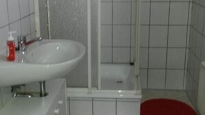 Ein Badezimmer mit einem weißen Waschbecken, einer Dusche und zwei roten Toilettensitzen.
